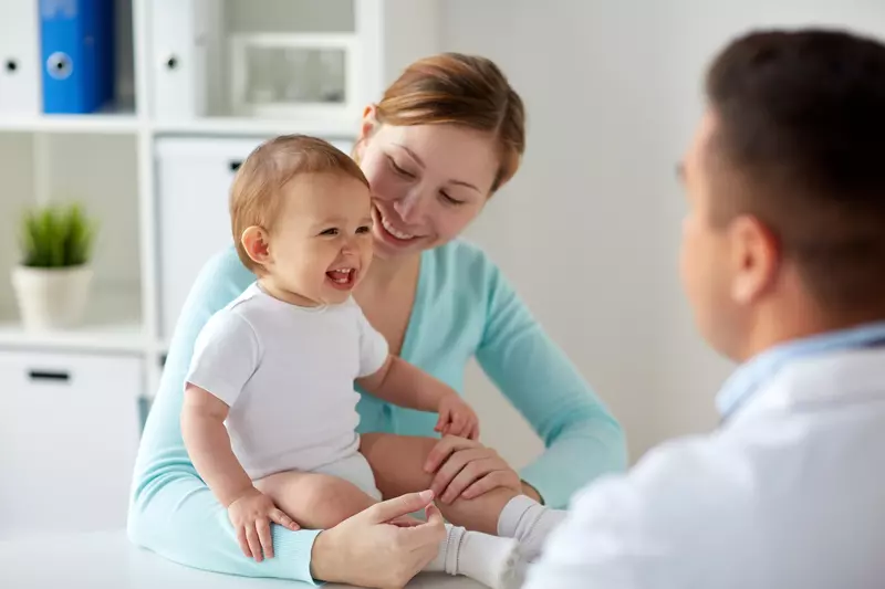 mom and smiling baby at pediatrician