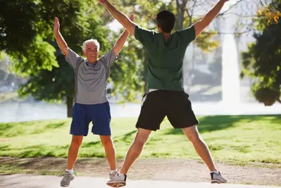 two older men doing jumping jacks outdoors