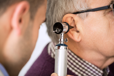 doctor examining senior man's ear using otoscope