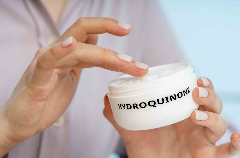 woman's hands applying hydroquinone from labeled jar