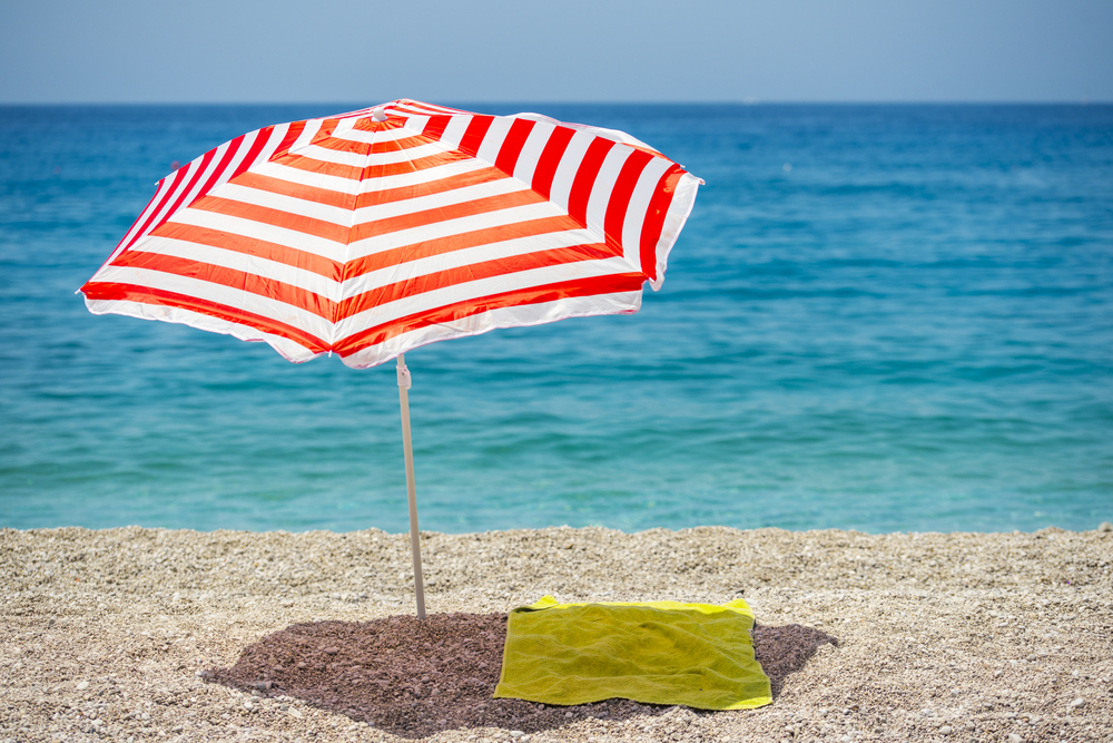 umbrella providing shade over towel on the beach