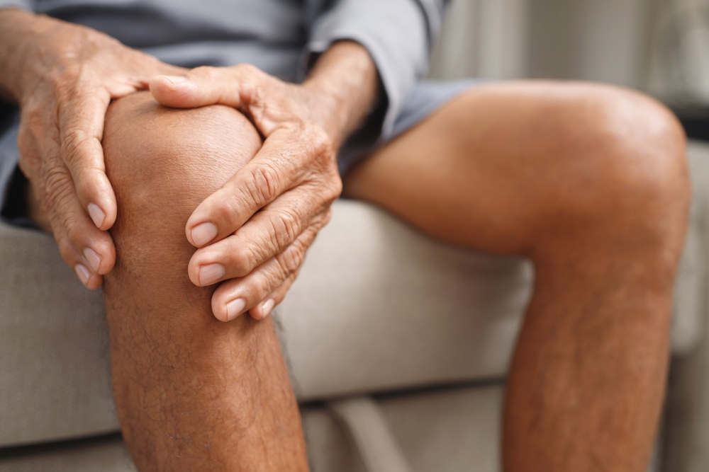 hands holding arthritic knee