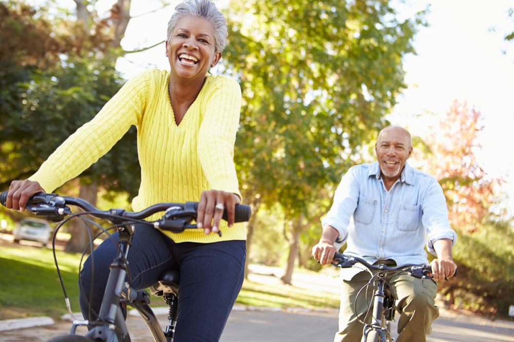 senior couple smiling while riding bikes outdoors