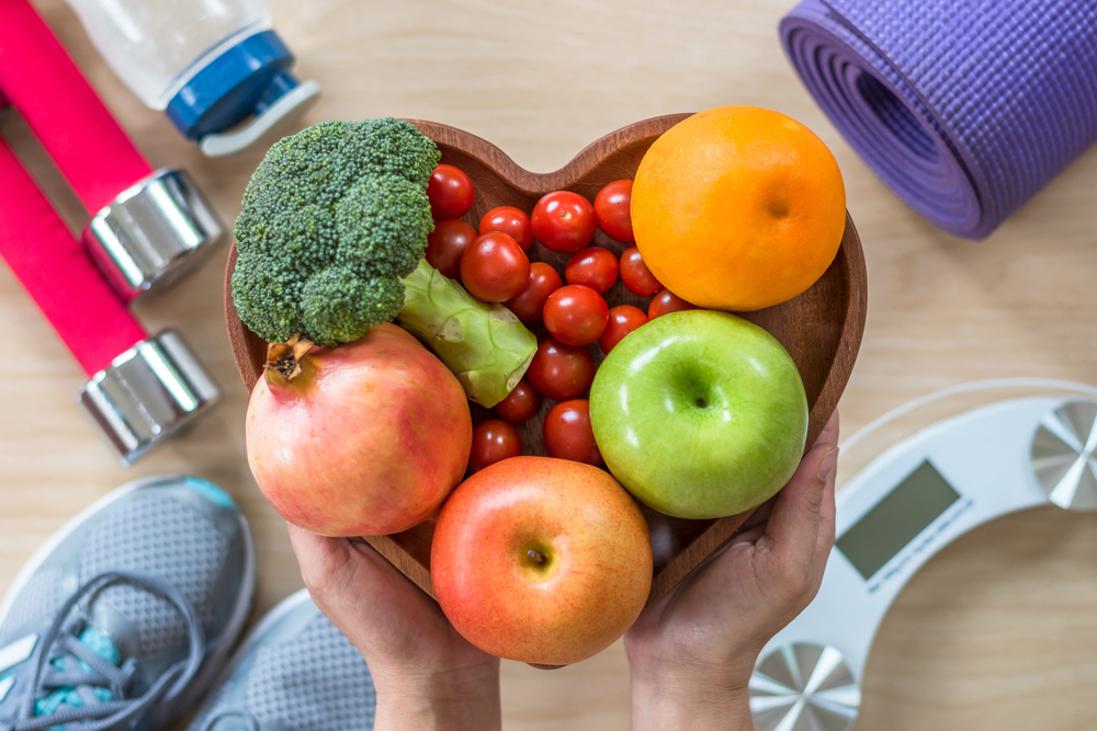 bowl of fruits and veggies held over exercise equipment and floor scale