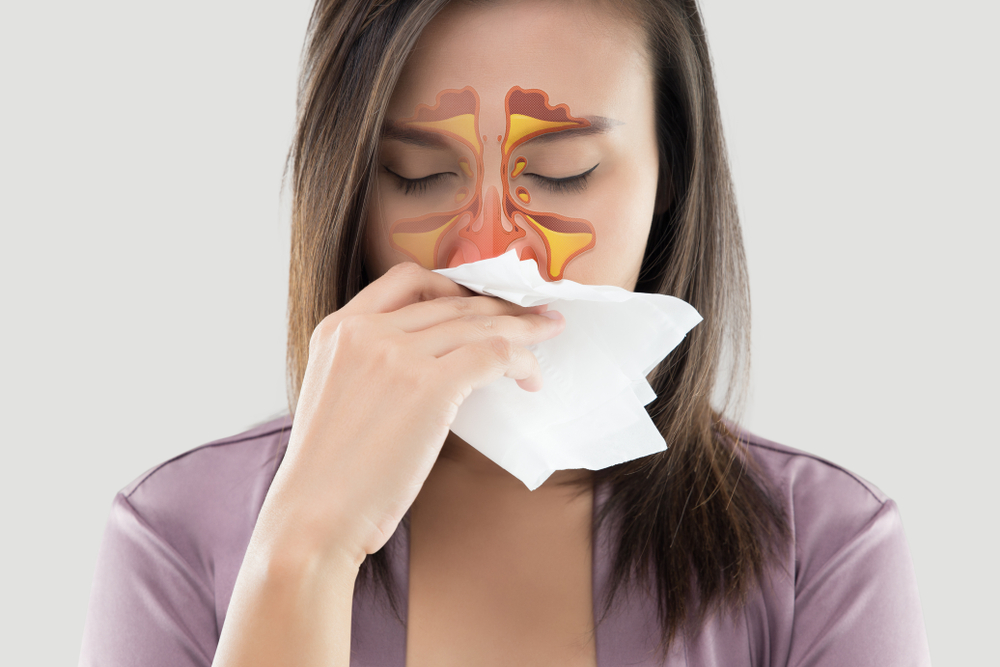 illustration of inflamed sinuses on woman's face as she blows her nose into a tissue