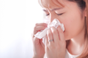 young woman blowing nose into tissue